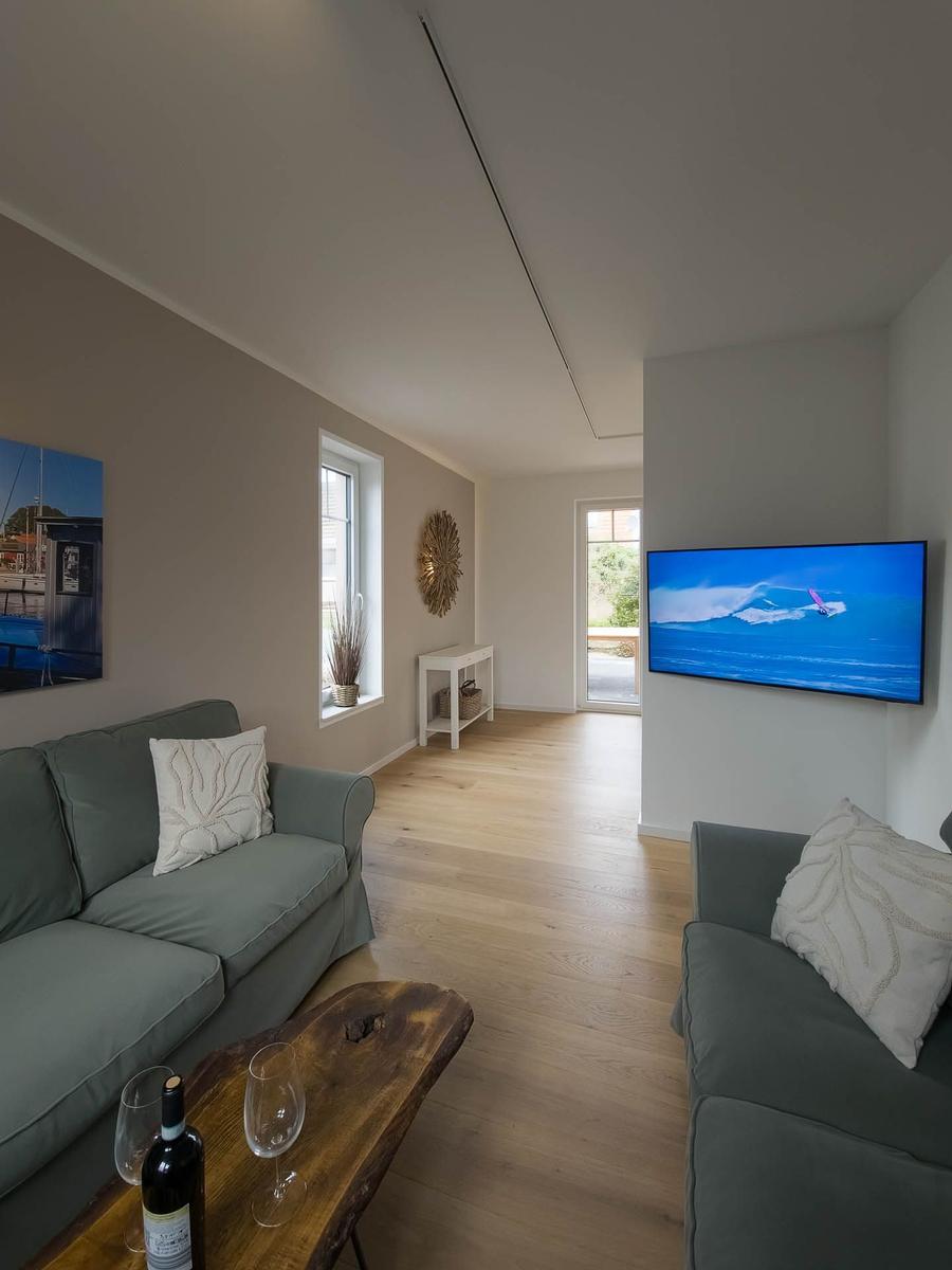 Wohnzimmer mit zwei Sofas, Holzboden und Fernseher an der Wand.