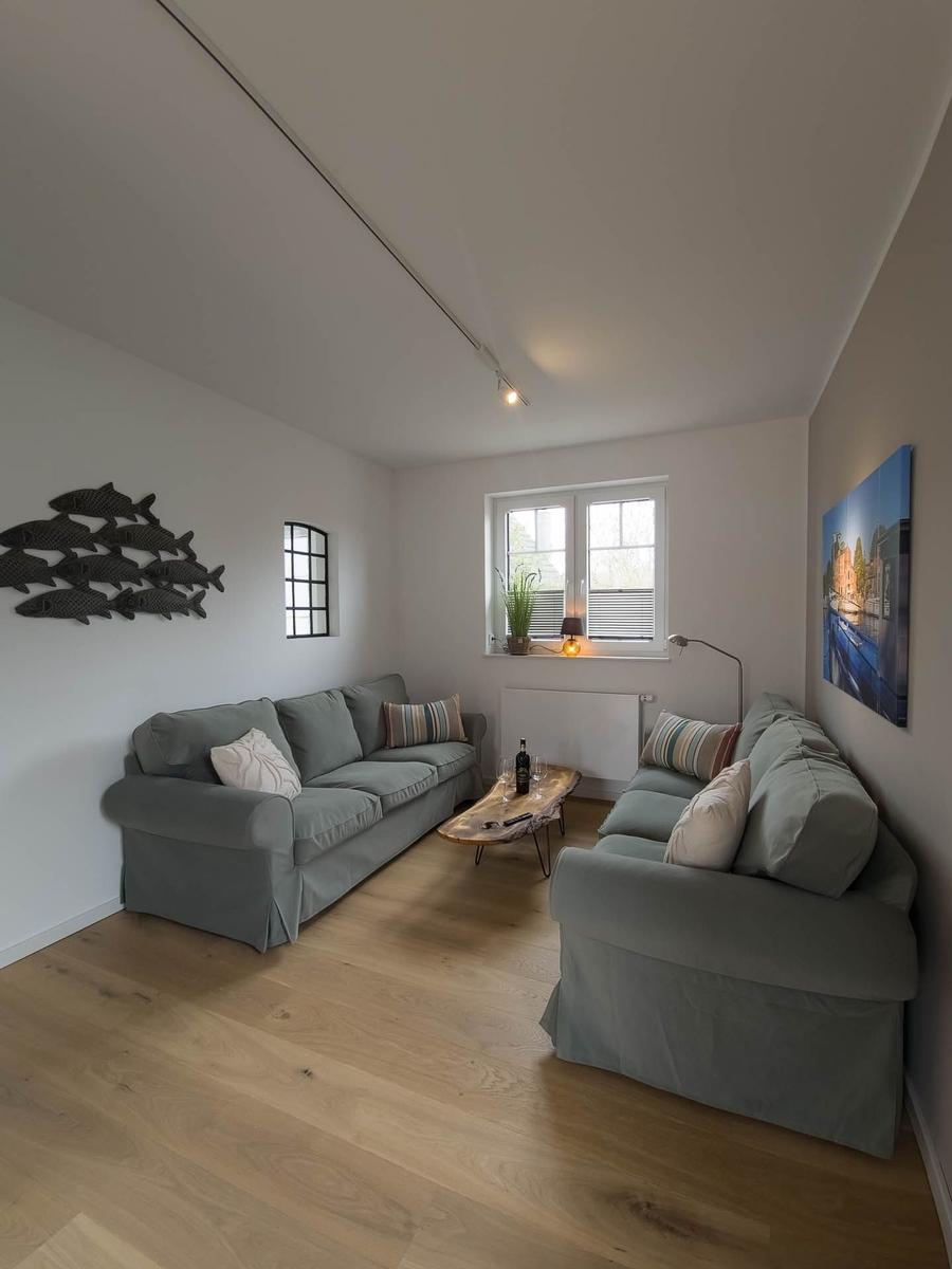 Wohnzimmer mit zwei Sofas, Holzboden und Fenster. Wanddekoration und Tisch.