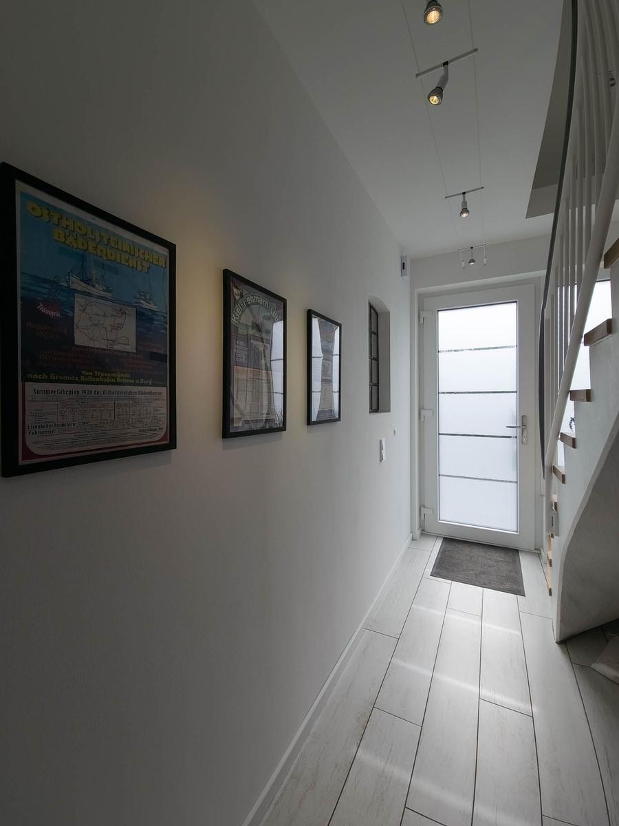 Flur mit Wandbildern, Bodenfliesen und Treppe zur oberen Etage.
