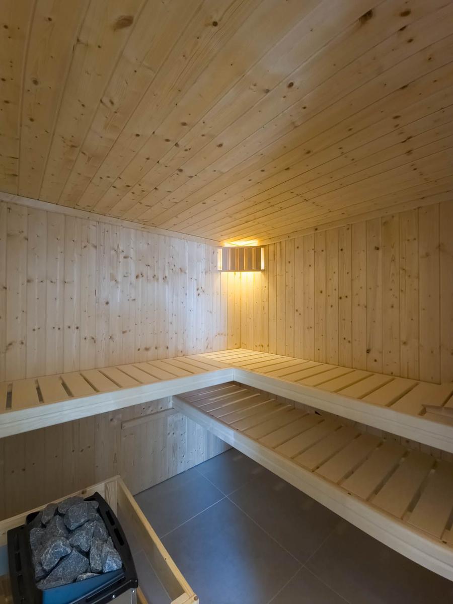 Sauna mit Holzwand, Bänken und Steinen im Ecke