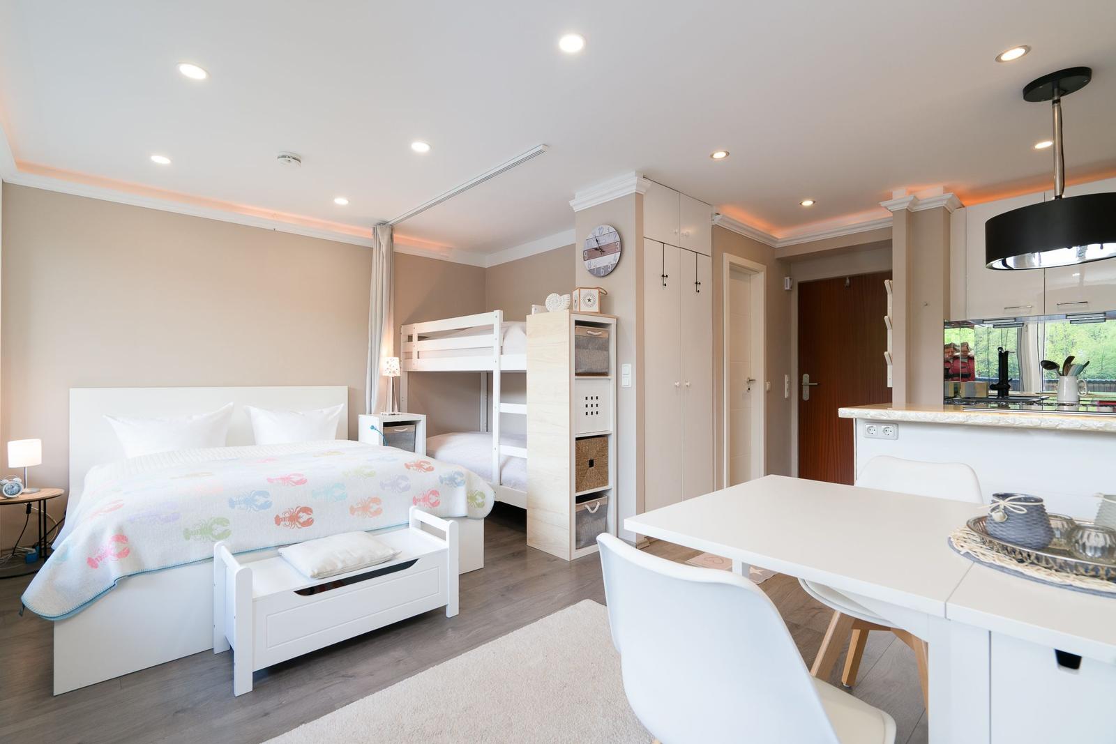 Schlafzimmer mit Doppelbett und Kletterwand. Küche mit Esstisch und moderner Beleuchtung.