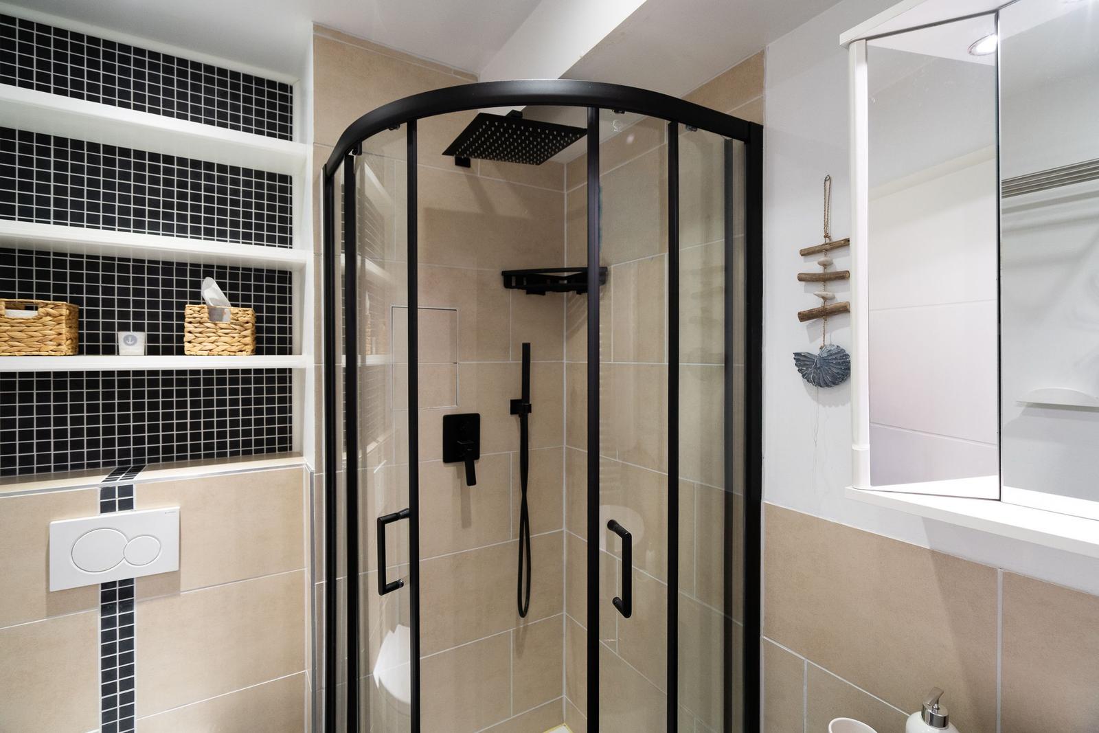 Dusche mit Glaswand, schwarzen Armaturen und Fliesenwand