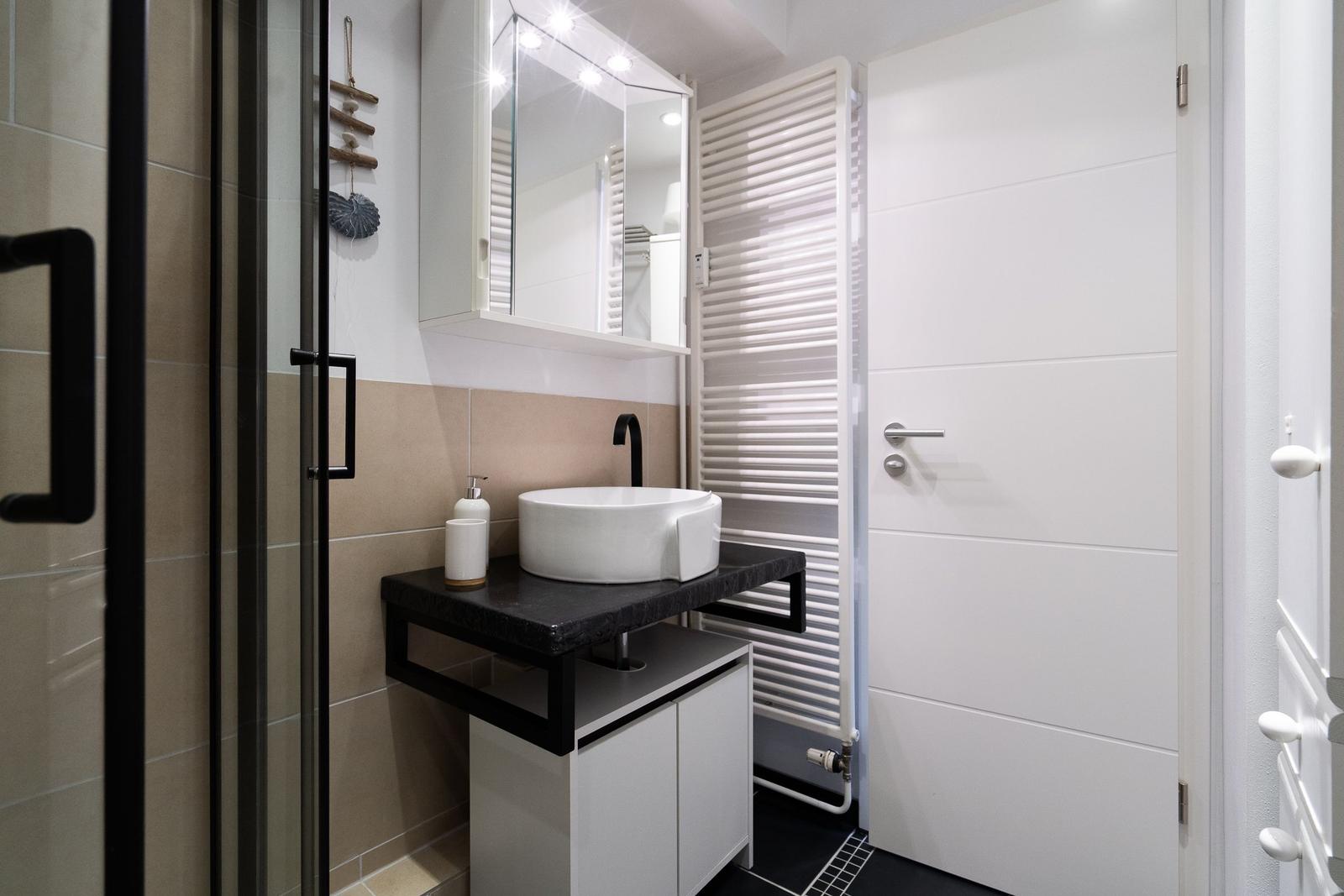 Badezimmer mit Waschbecken, Spiegel und Dusche