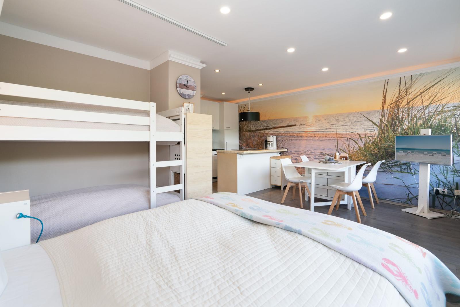 Zimmer mit Doppelbett, Etagenbett und Küchenbereich mit Kücheninsel.