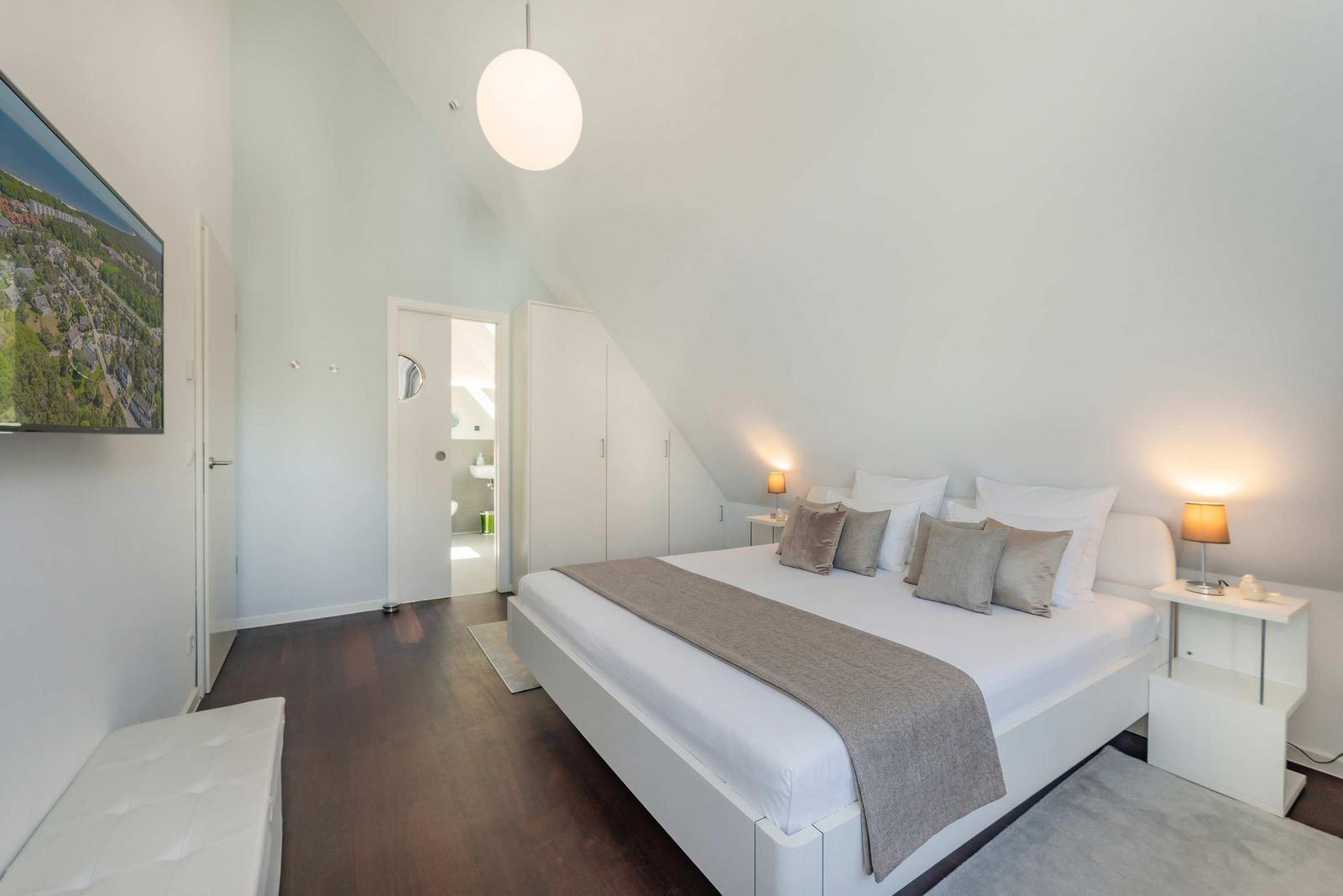 Schlafzimmer mit Bett, Nachttischen und Fernseher an der Wand.