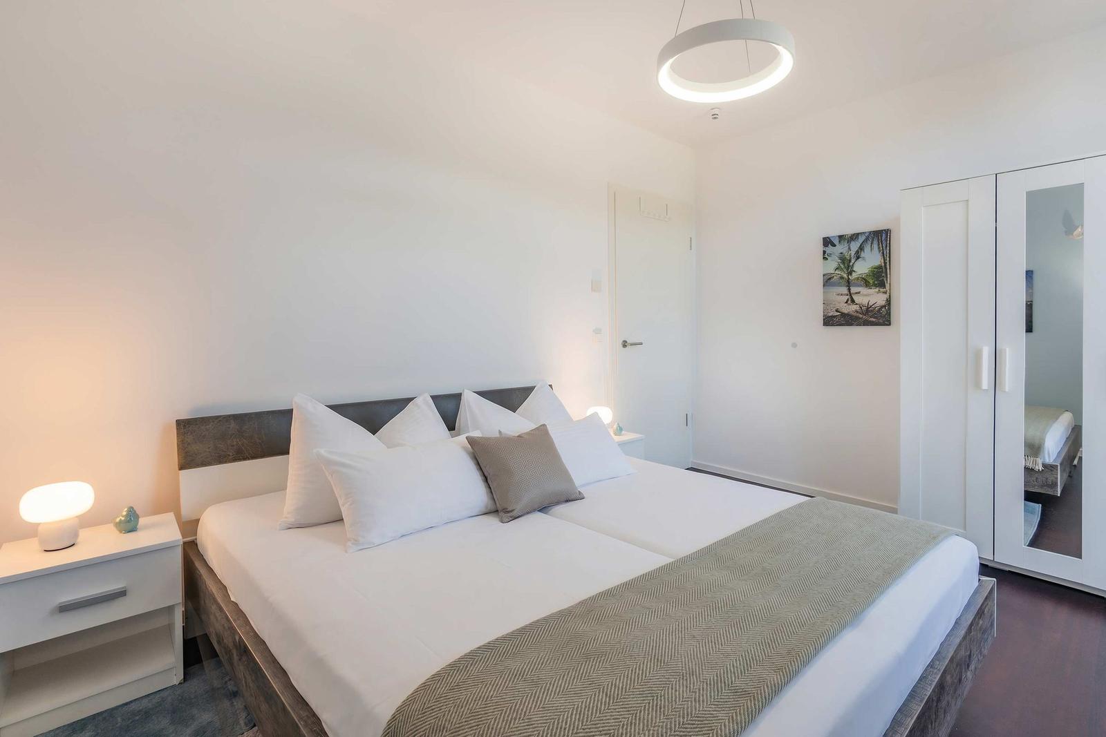 Schlafzimmer mit Doppelbett, Nachttisch, Spiegelschrank und Deckenventilator.