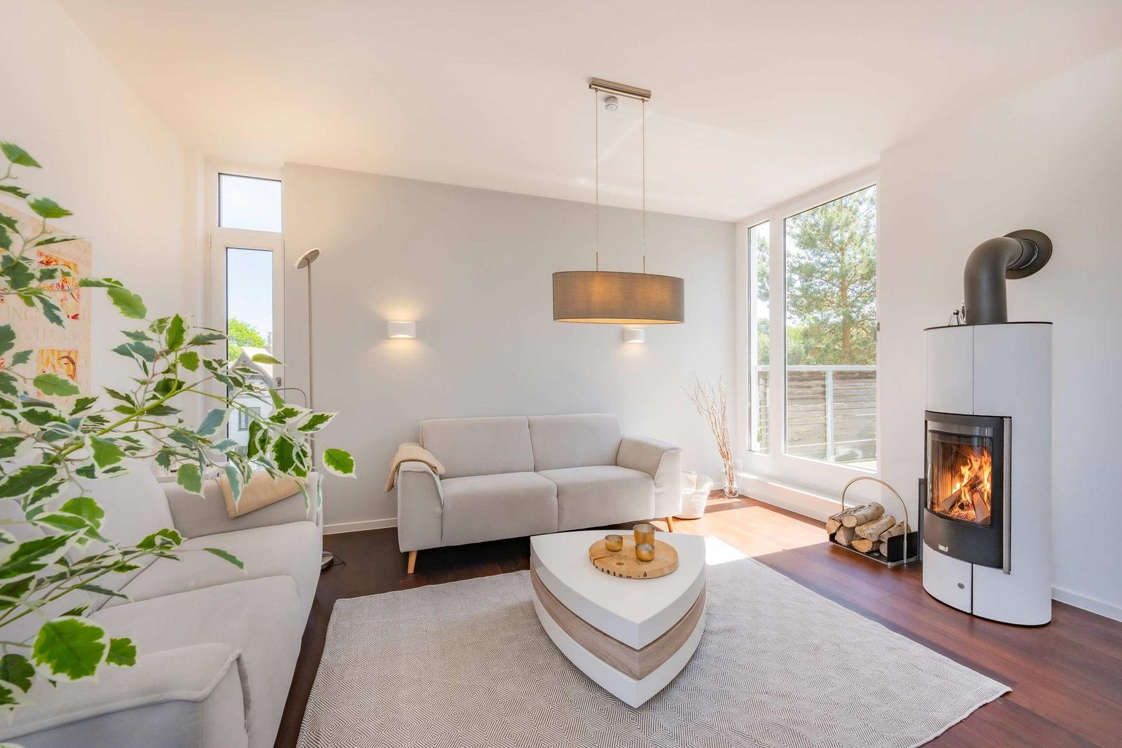 Wohnzimmer mit Sofa, Kamin und großem Fenster. Holzboden und moderner Couchtisch.