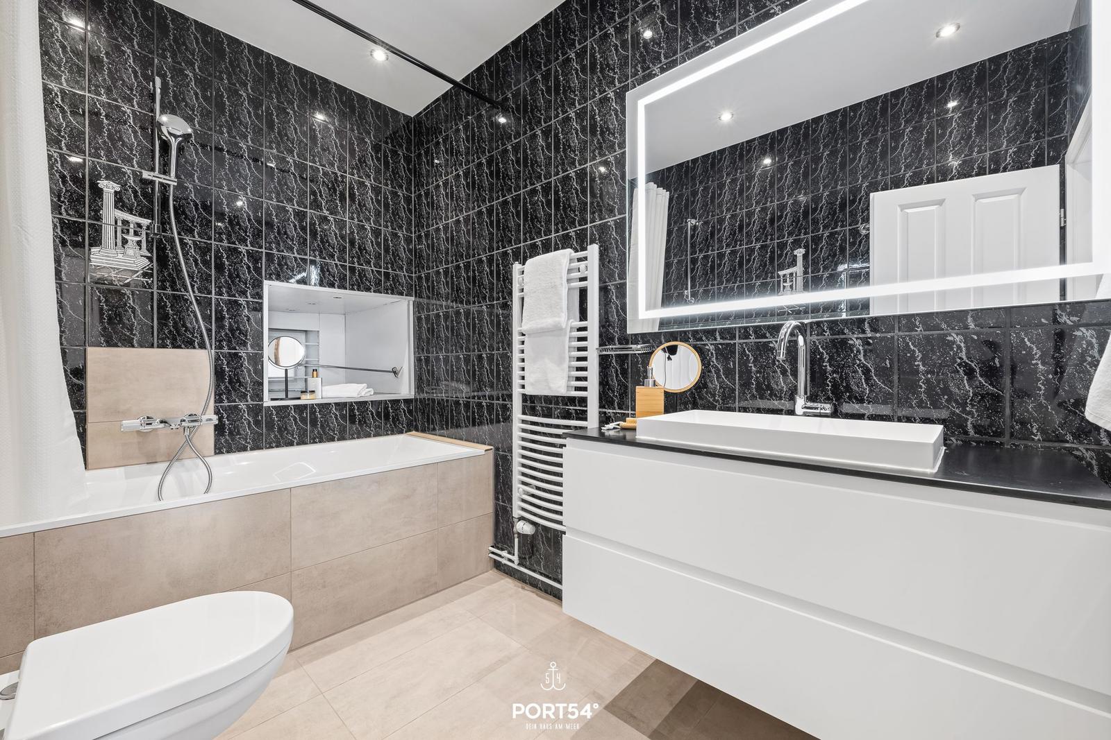 Badezimmer mit Dusche, Badewanne, Waschbecken und Spiegel