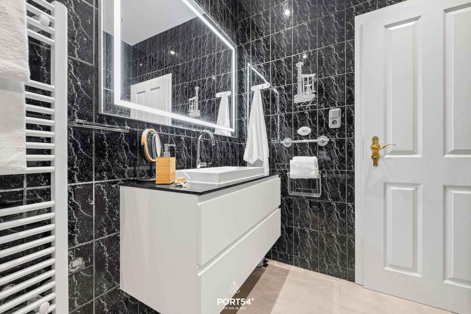 Badezimmer mit schwarzem Marmor und weißem Waschtisch