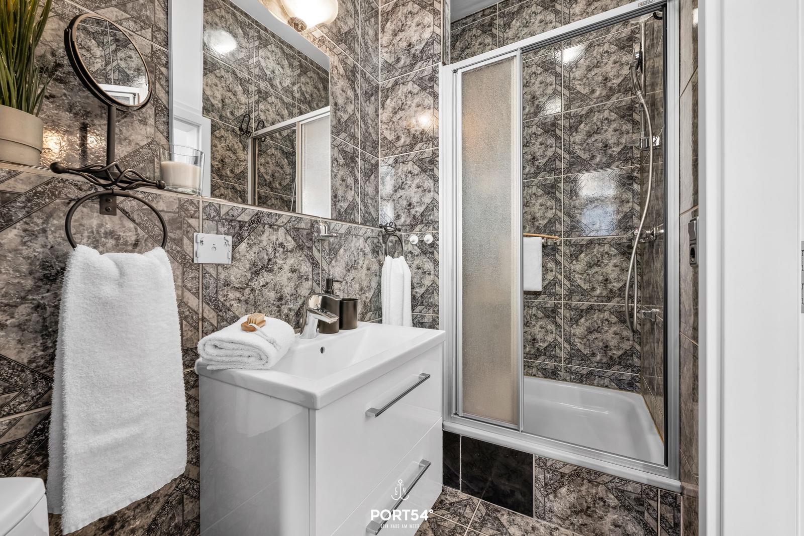 Badezimmer mit Dusche, Waschbecken und Handtuchhalter