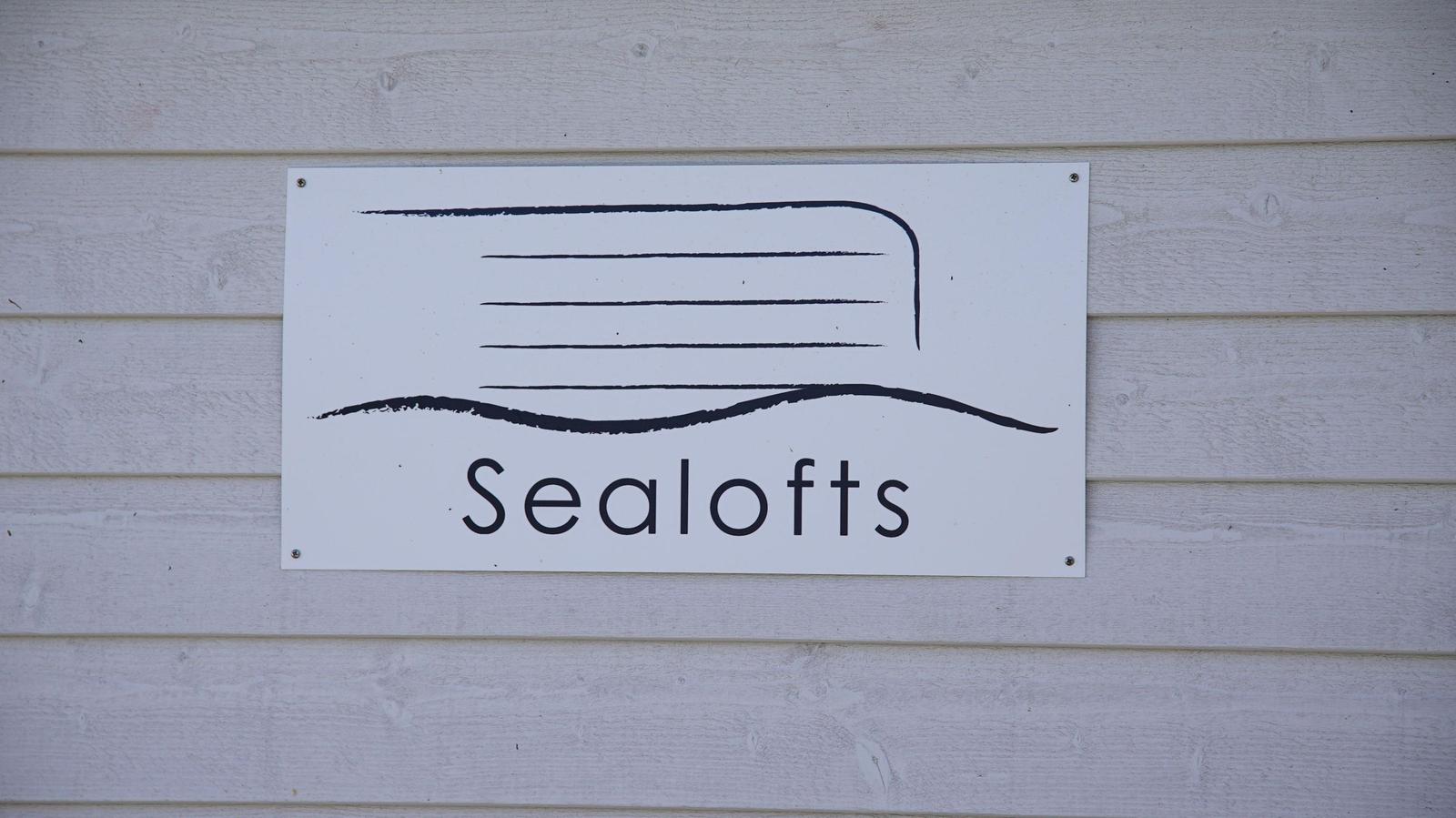 Schild mit dem Namen Sealofts an einer weißen Holzwand.