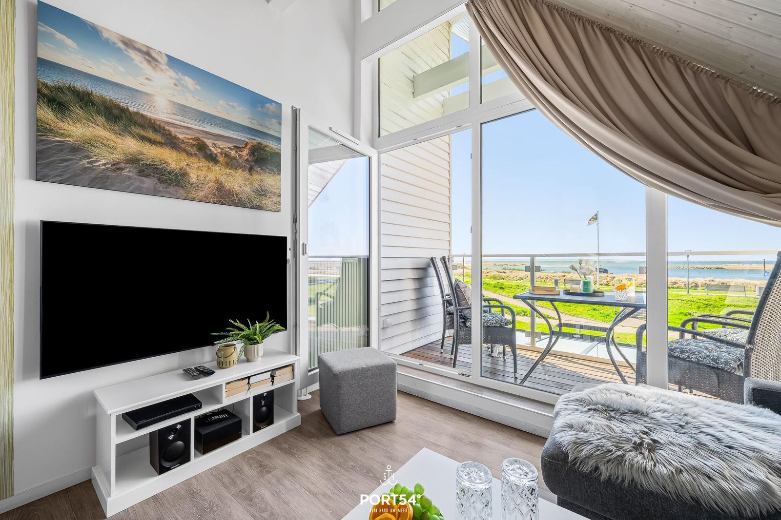 Living room with TV, balcony, and sea view.