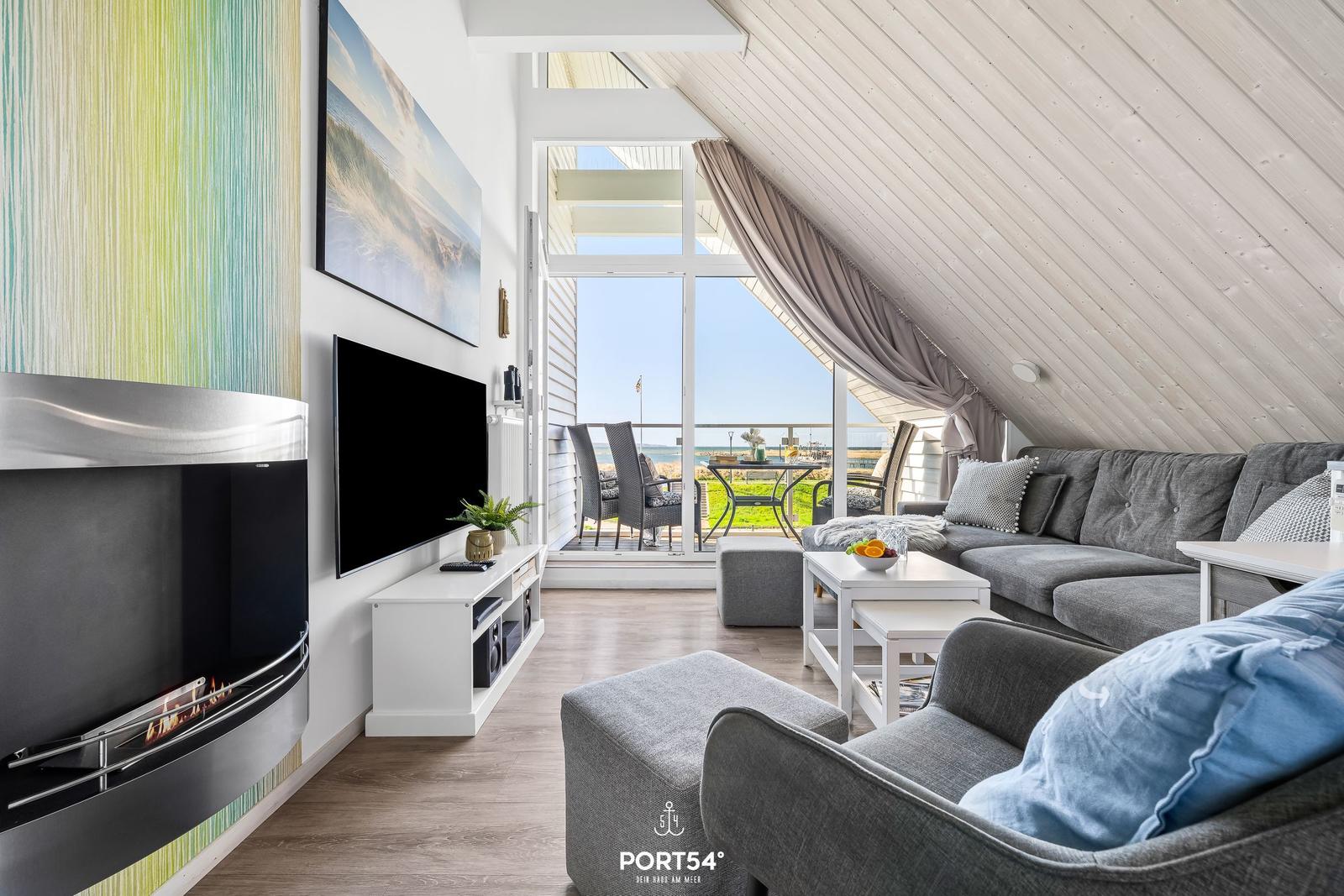 Living room with fireplace, TV, and balcony view of the sea.