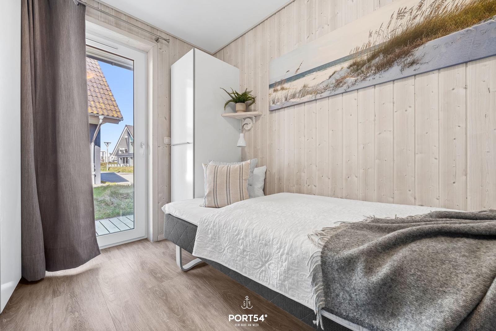 Bedroom with bed, wall art, and door to outdoor area.