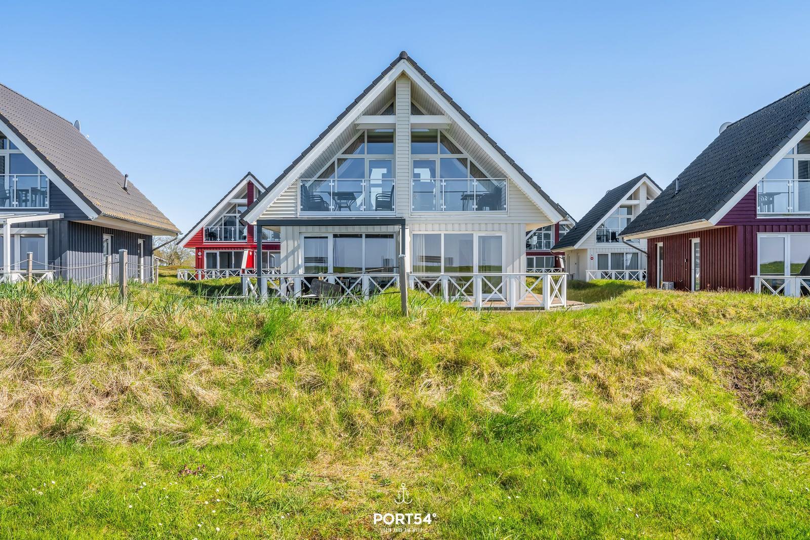 Modern vacation homes with large windows and terraces in a green setting.