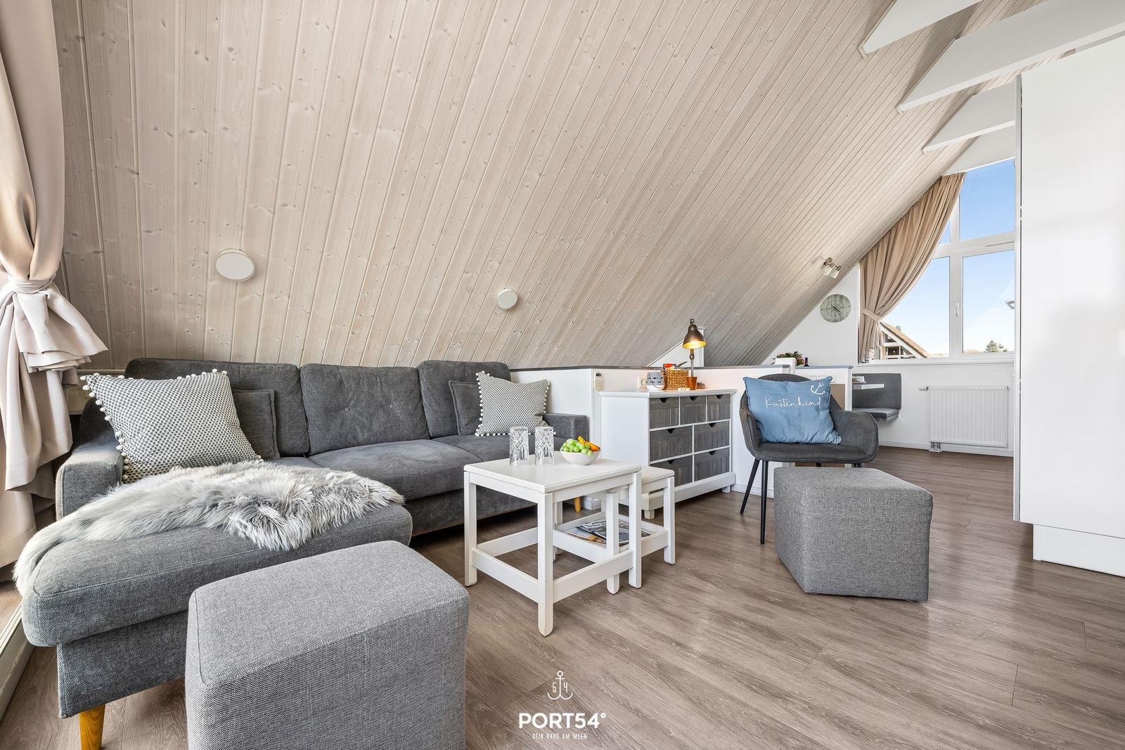 Living room with gray sofa, white tables, and wooden ceiling.