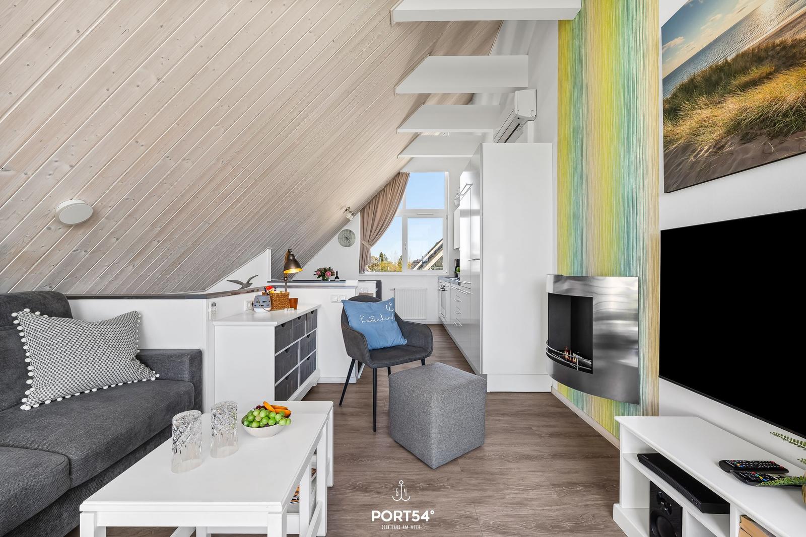 Living area with sofa, coffee table, and fireplace. Wooden ceiling and window with view.