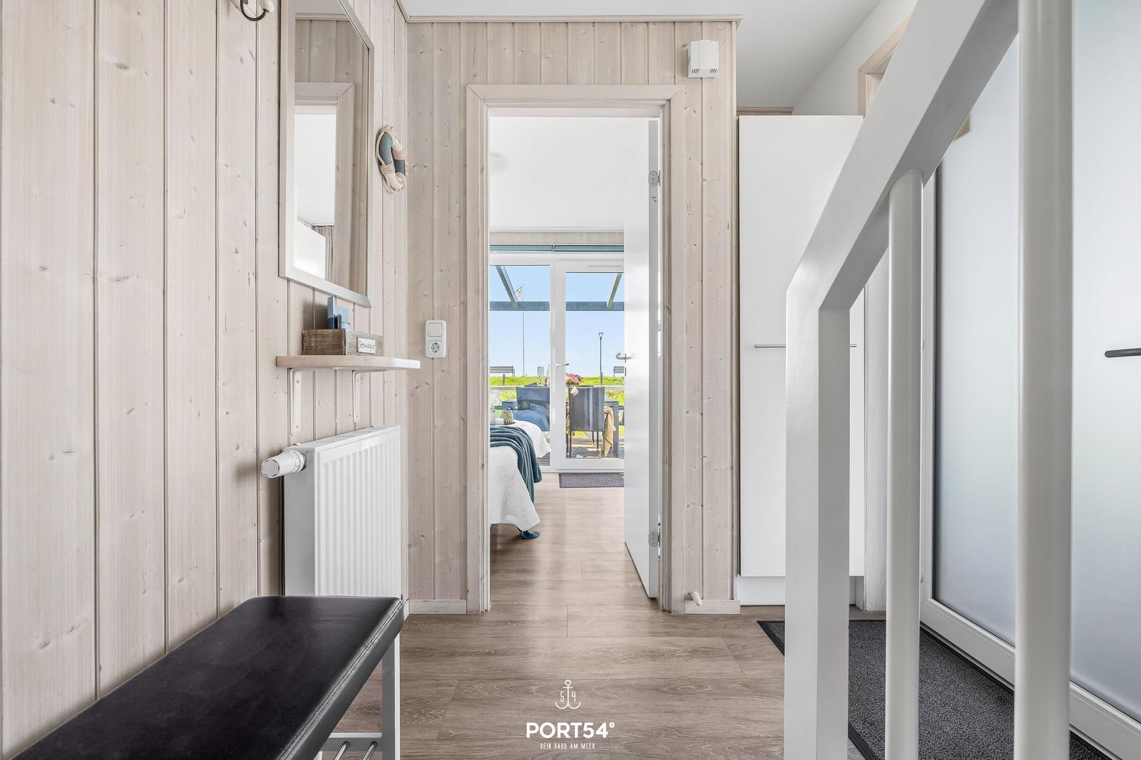Hallway with wooden walls, mirror, and view into bedroom with terrace.