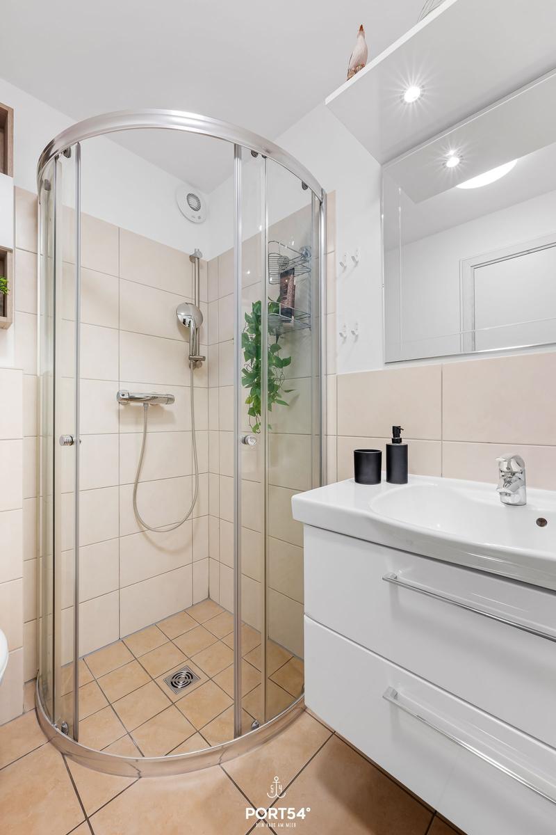 Bathroom with shower, sink, and mirror.