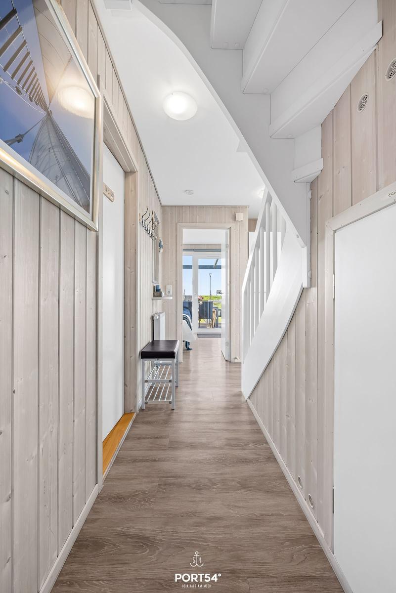 Hallway with wooden walls, staircase, and bench to balcony