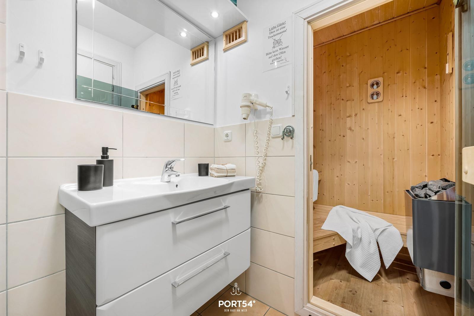 Bathroom with sink and steam sauna in the background.