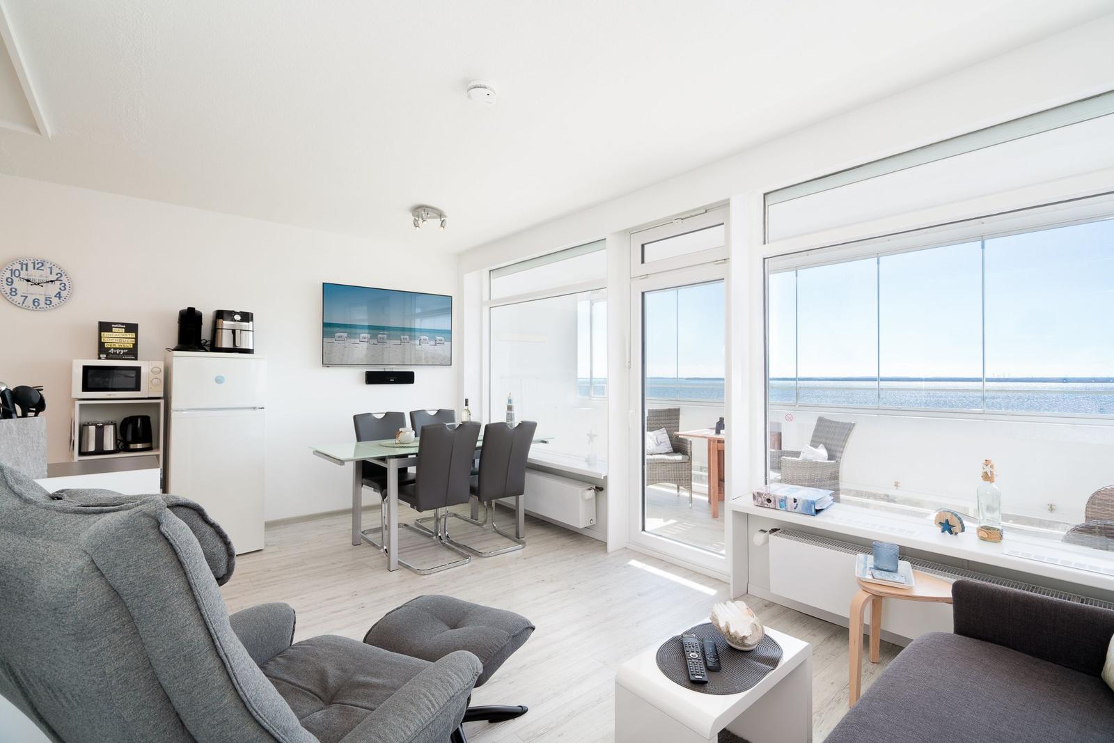 Living room with dining area, sea view, and modern furnishings.