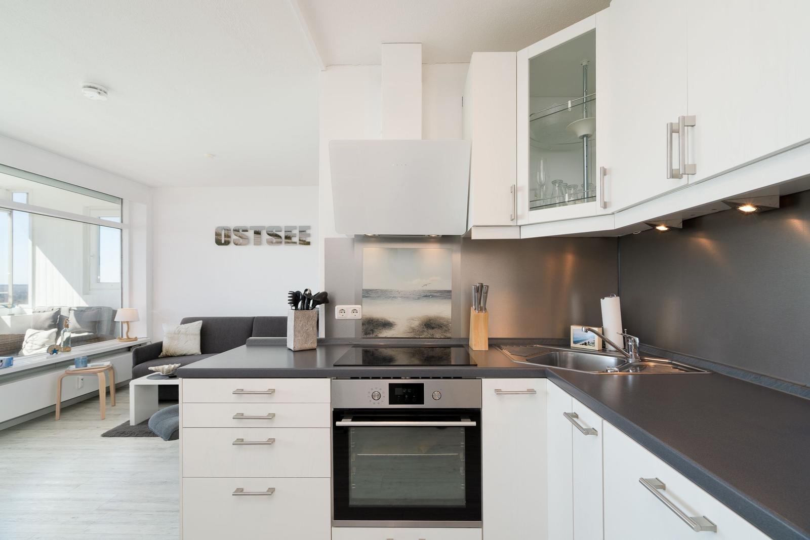 Kitchen with white cabinets, dark countertop, and view into living room with sofa.