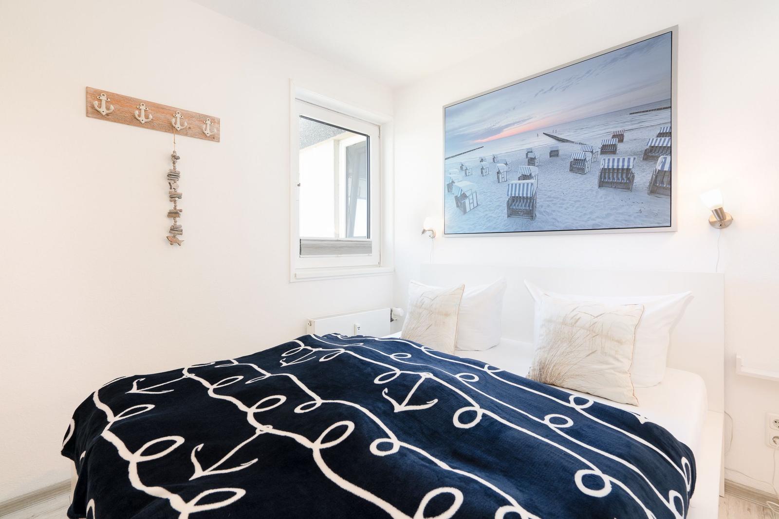 Bedroom with bed, wall picture, and window.
