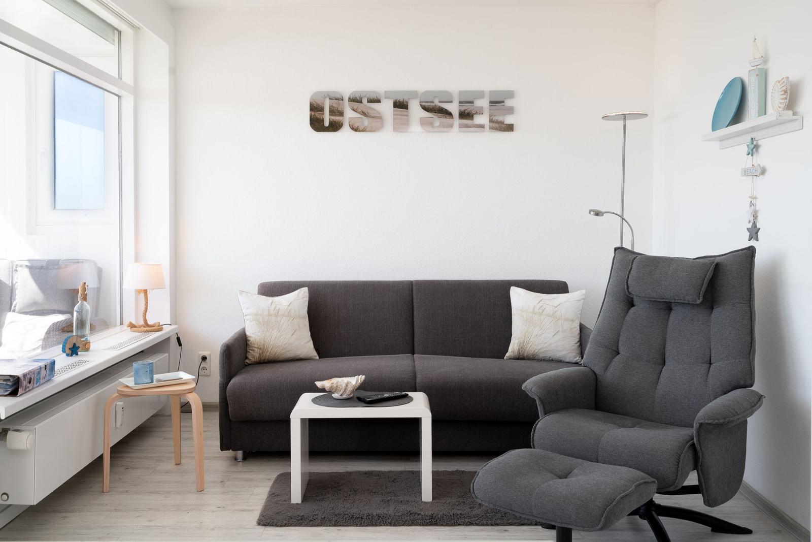 Living room with sofa, recliner, and wall decoration OSTSEE.
