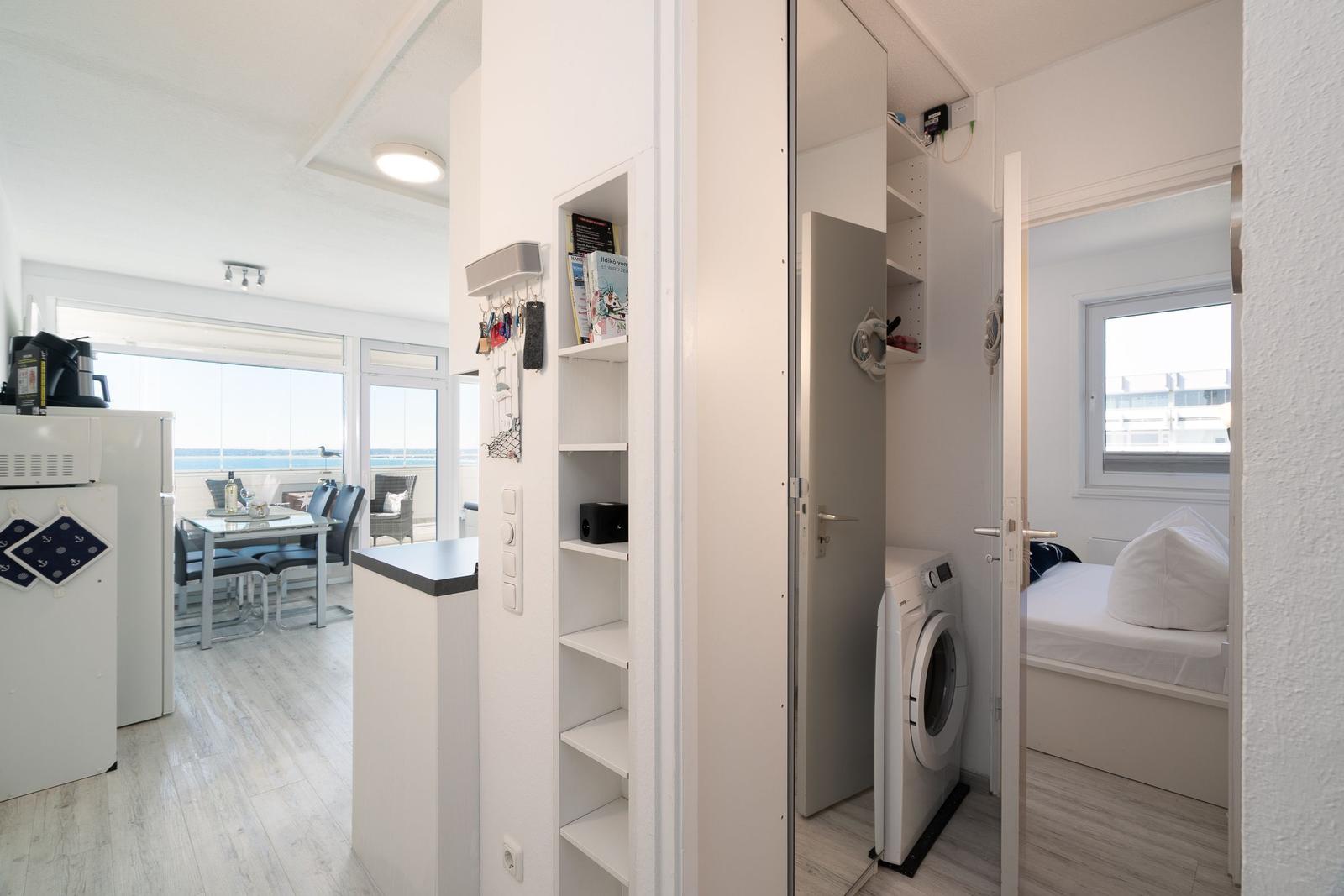 Apartment with kitchen area, bedroom, and washing machine.