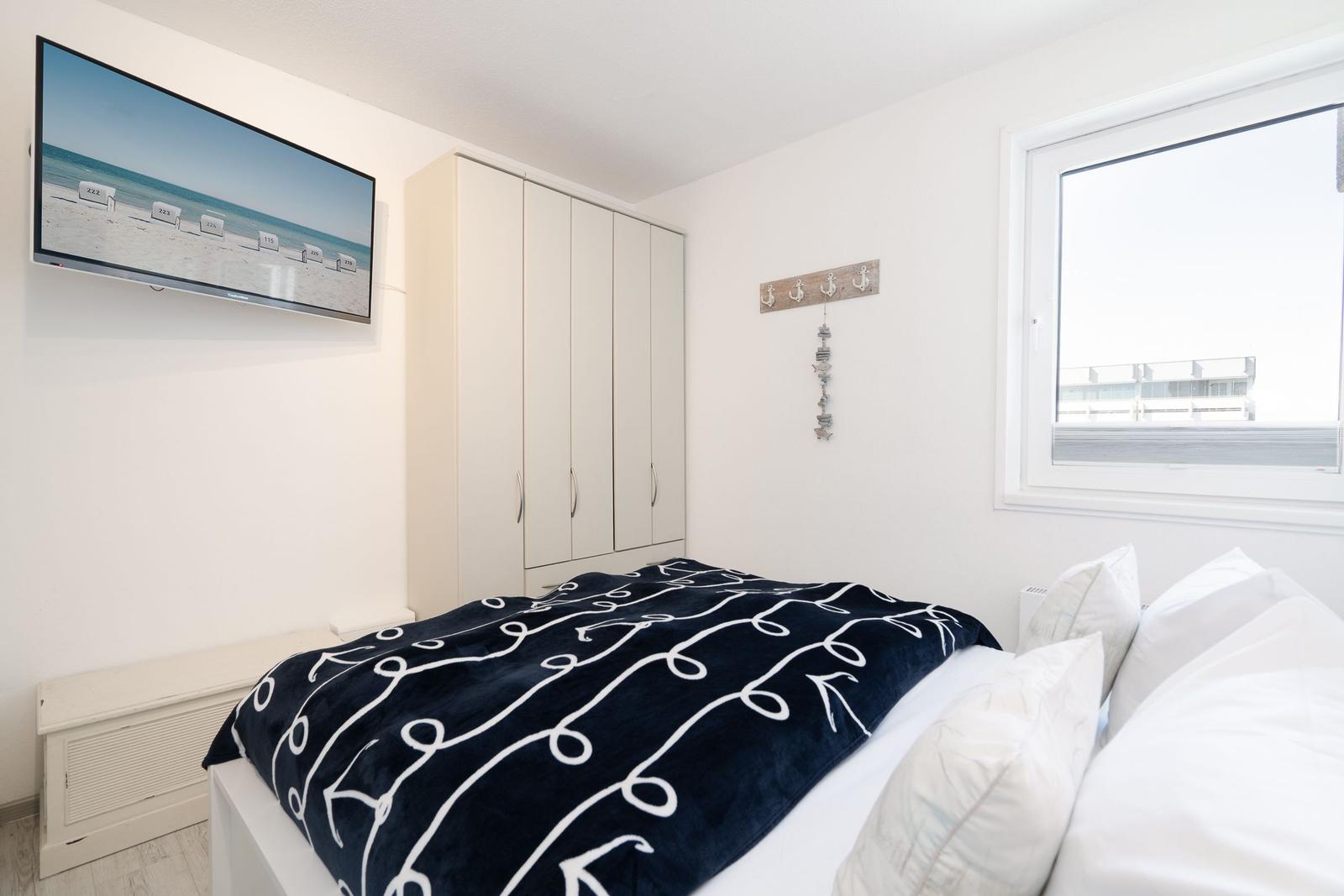 Bedroom with bed, wardrobe, and TV mounted on the wall.