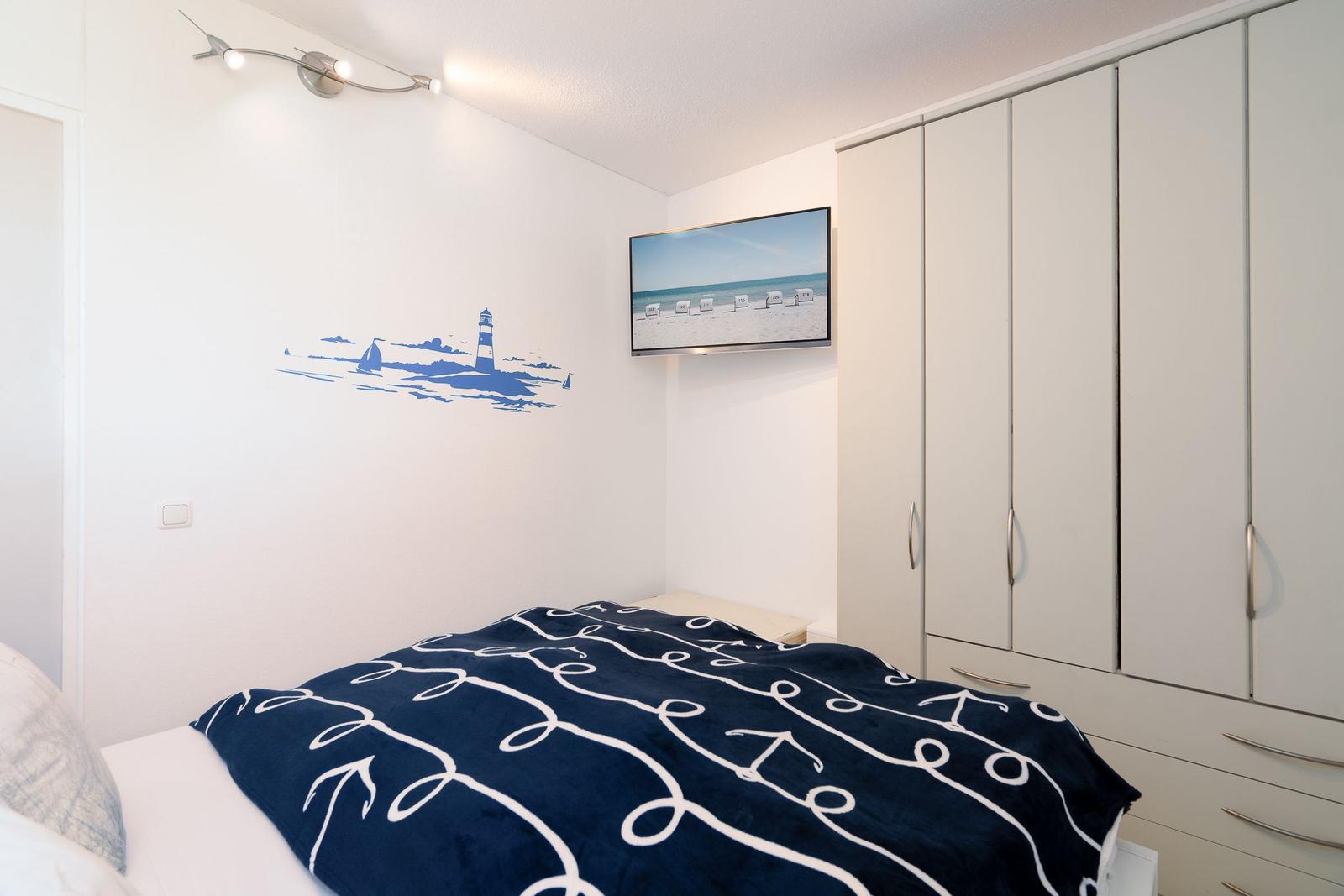 Bedroom with bed, wardrobe, and wall picture with light fixture.