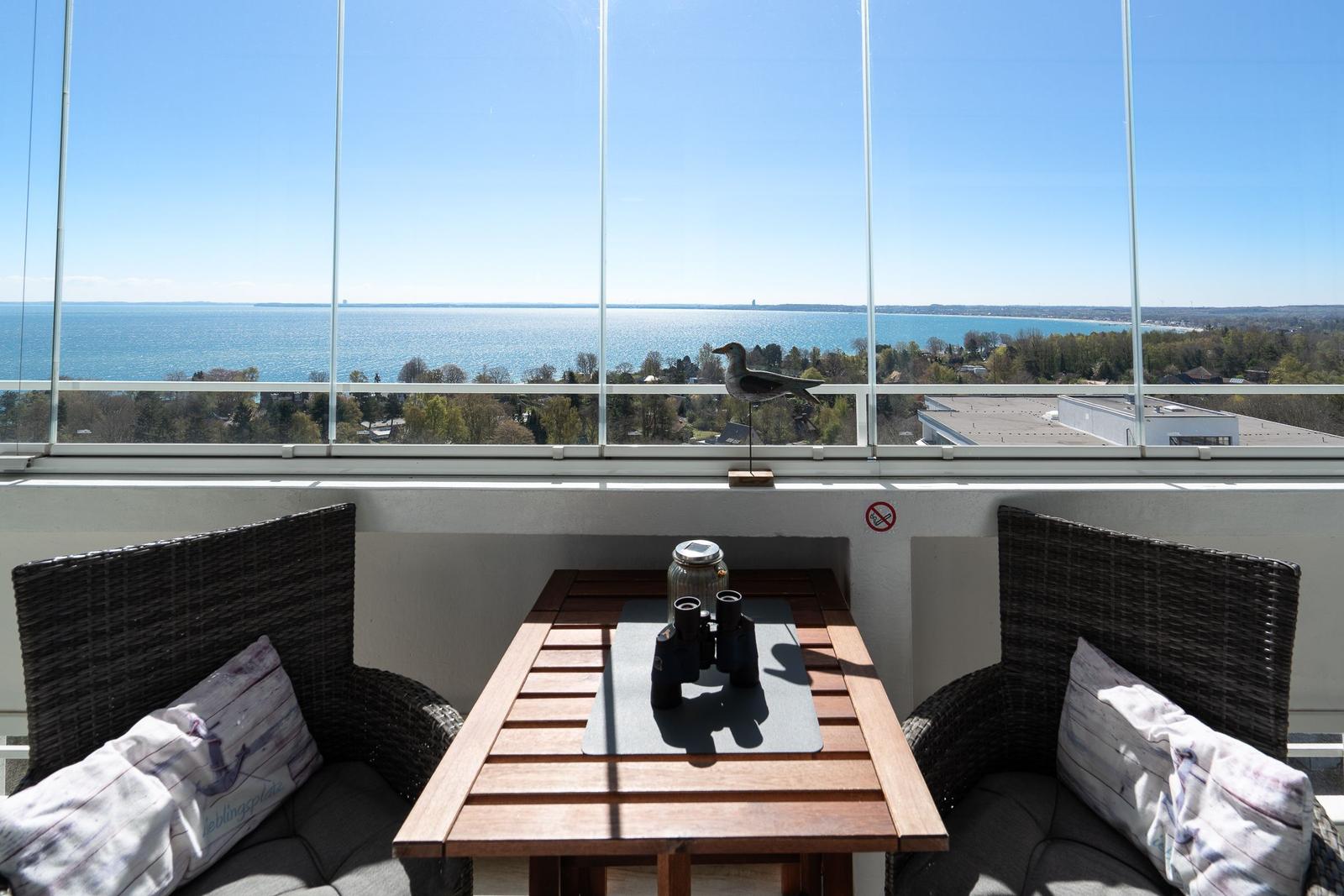 Balcony with table and two seating areas. View of lake and city.