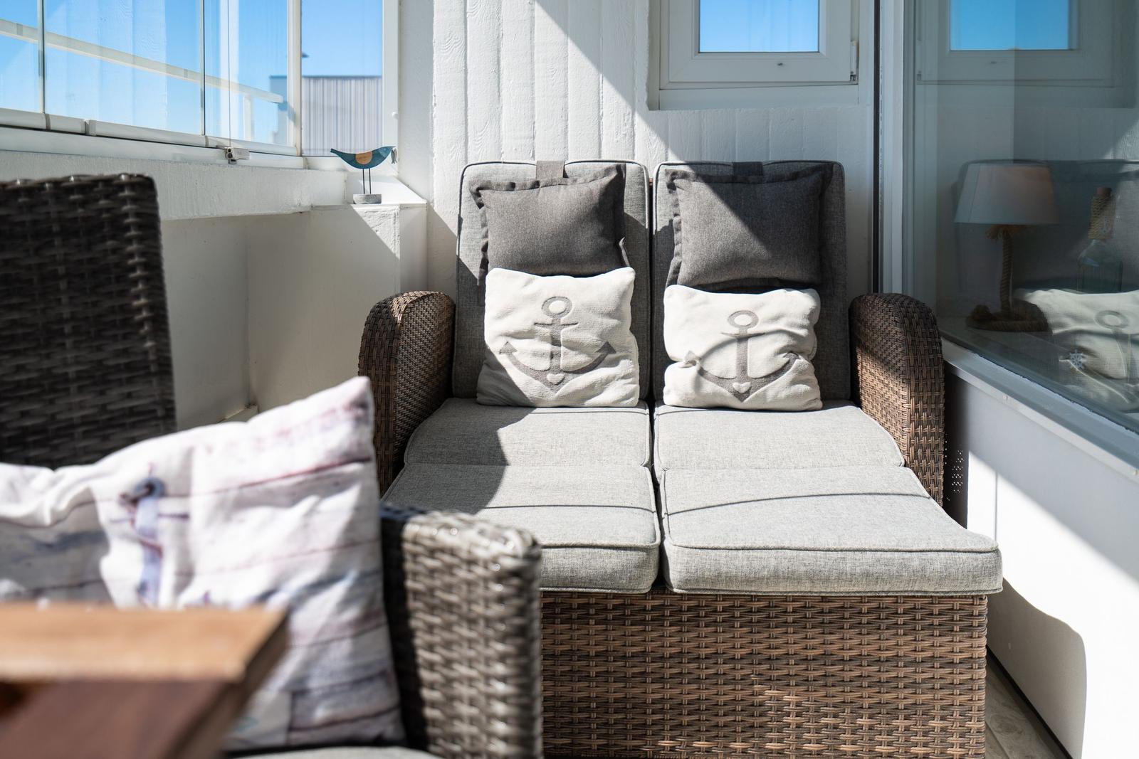 Terrace area with wicker sofa and anchor-patterned cushions.