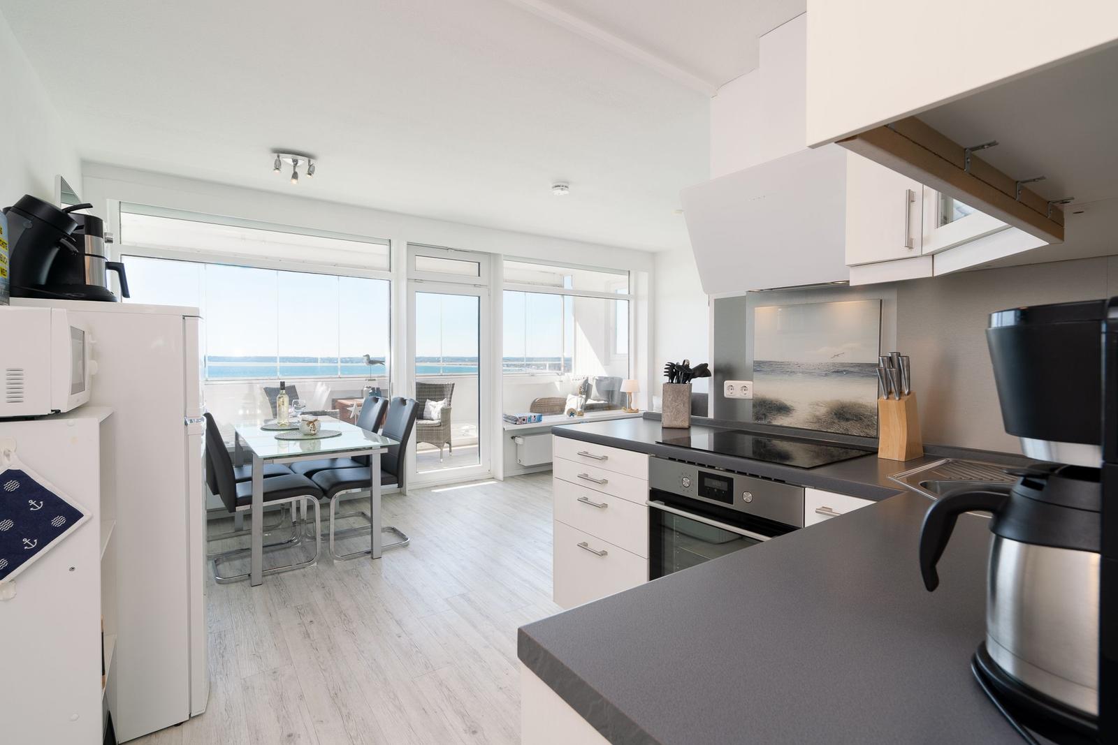 Kitchen with dining area and sea view through large windows.