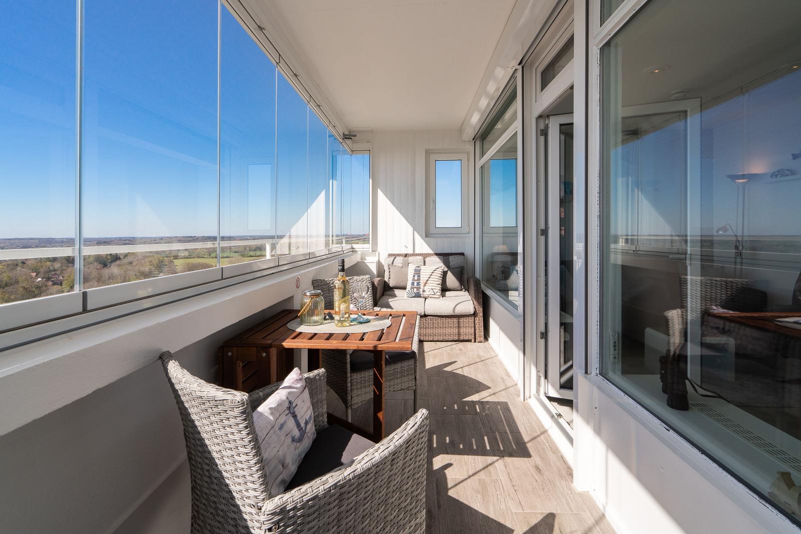 Terrasse mit Sitzgruppe und Tisch. Blick auf Landschaft. Glasgeländer und Holzboden.