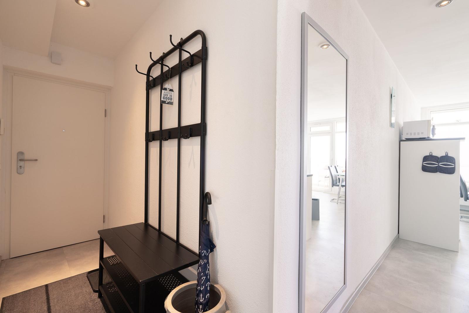 Eingangsbereich mit Garderobe, Spiegel und Blick in die Küche.