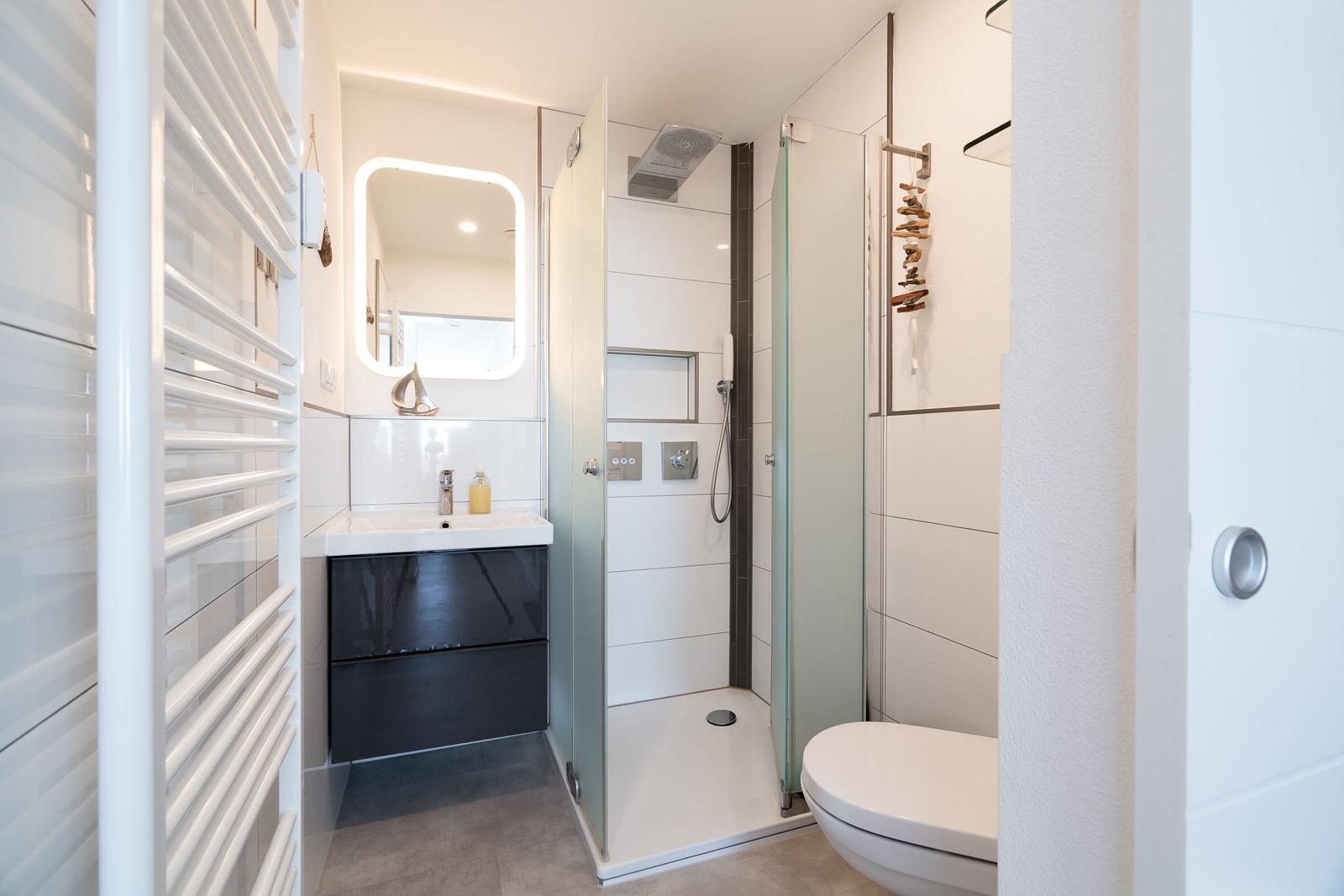 Badezimmer mit Dusche, Waschbecken und Toilette.