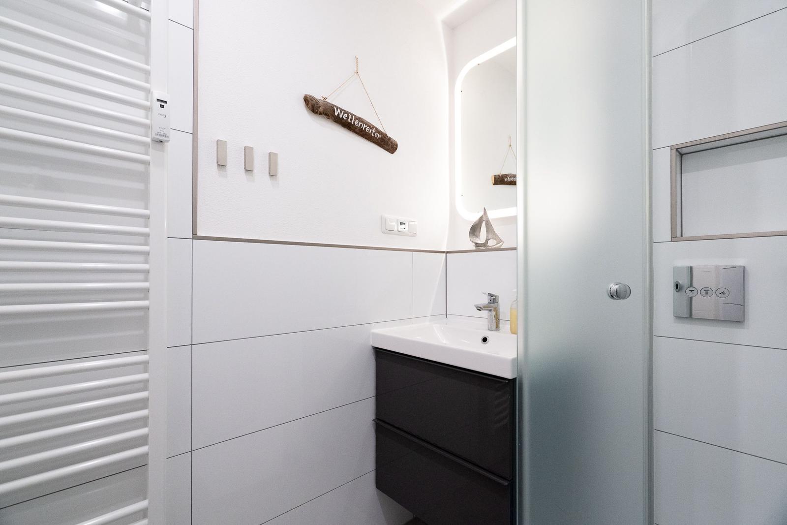 Badezimmer mit Waschbecken, Spiegel und Heizkörper