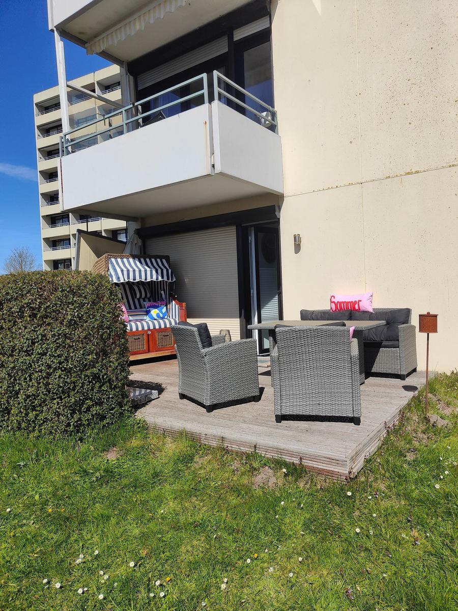 Terrasse mit Sitzgruppe, Strandkorb und grünem Rasenbereich.