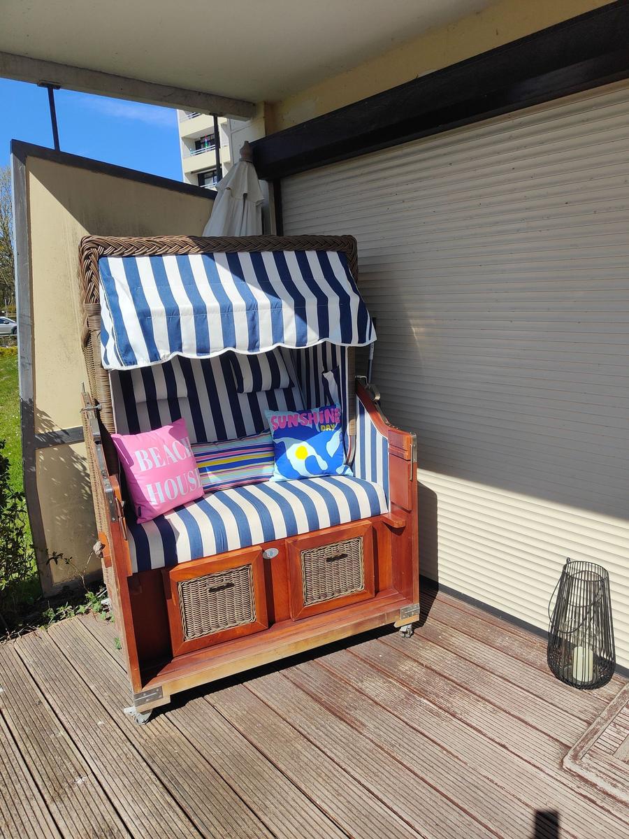 Hochwertiger Strandkorb mit blau-weißem Streifenmuster und Kissen auf Terrasse.