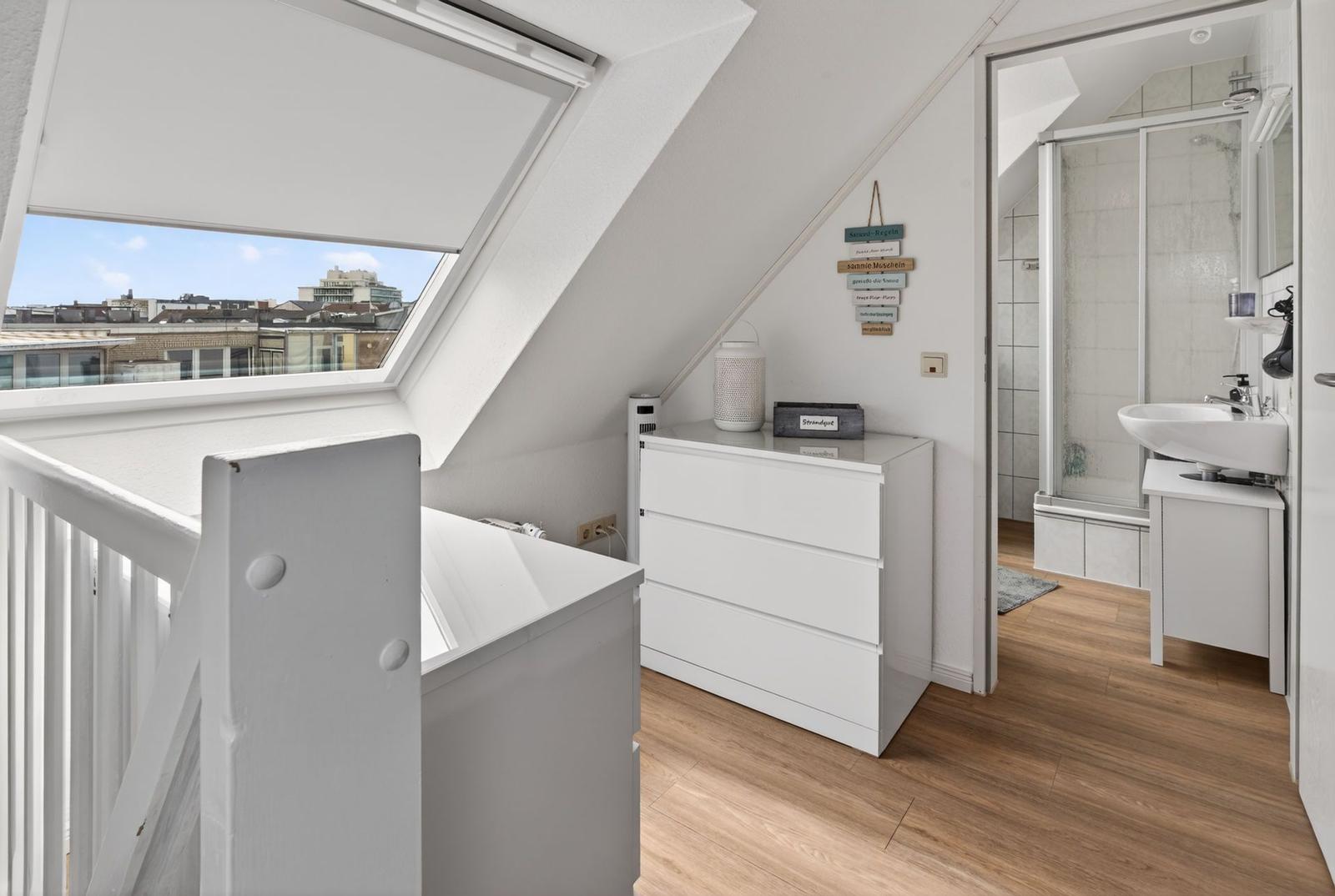 Attic room with sloped ceiling, skylight, and adjacent bathroom.
