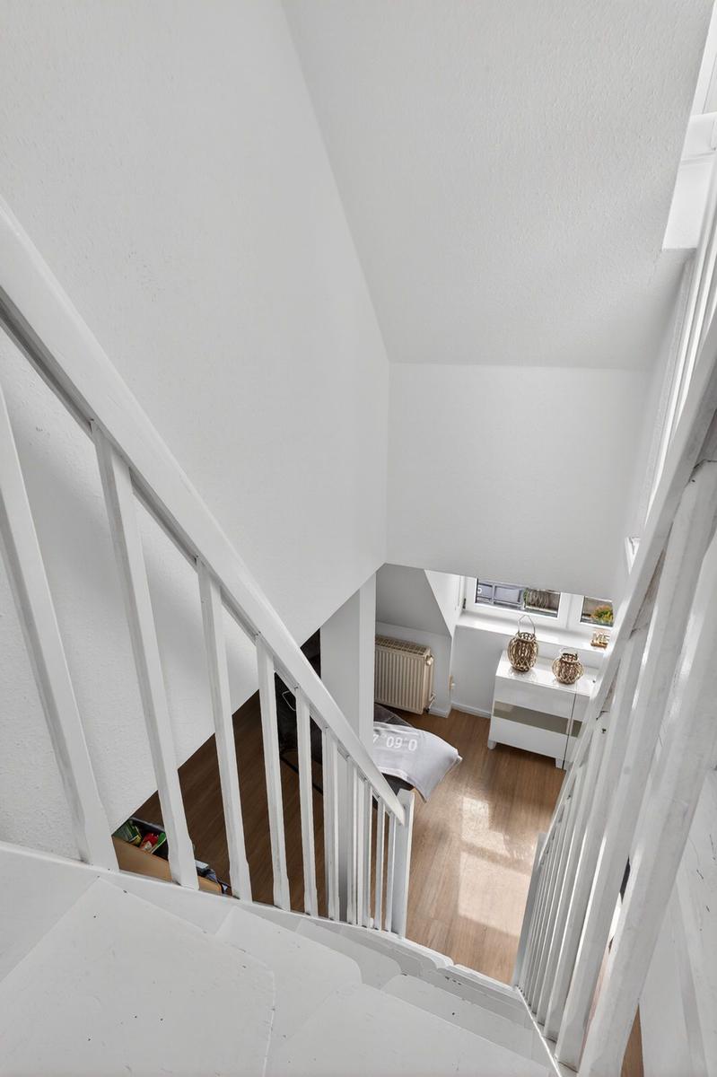 White staircase leading to living area with window and cabinet.