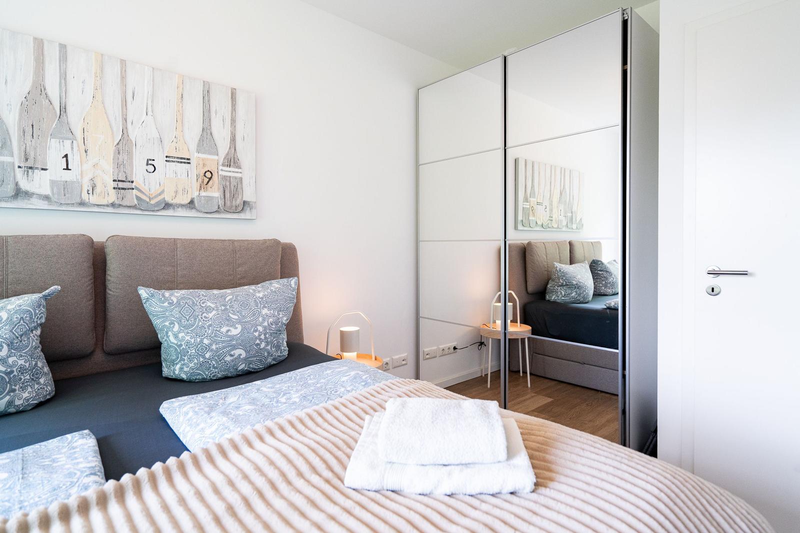 Bedroom with bed, mirrored wardrobe, and wall art with oars.