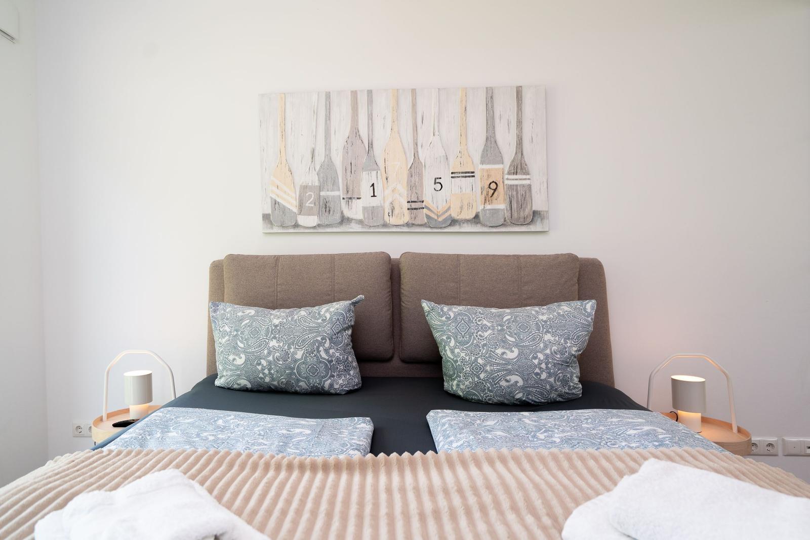 Double bed with pillows and wall art with oars.