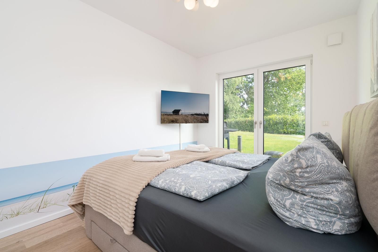 Bedroom with bed, TV, and glass door to the garden.
