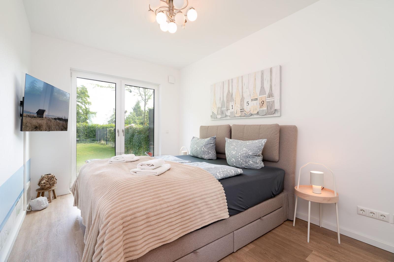 Bedroom with bed, TV, and window to the garden.