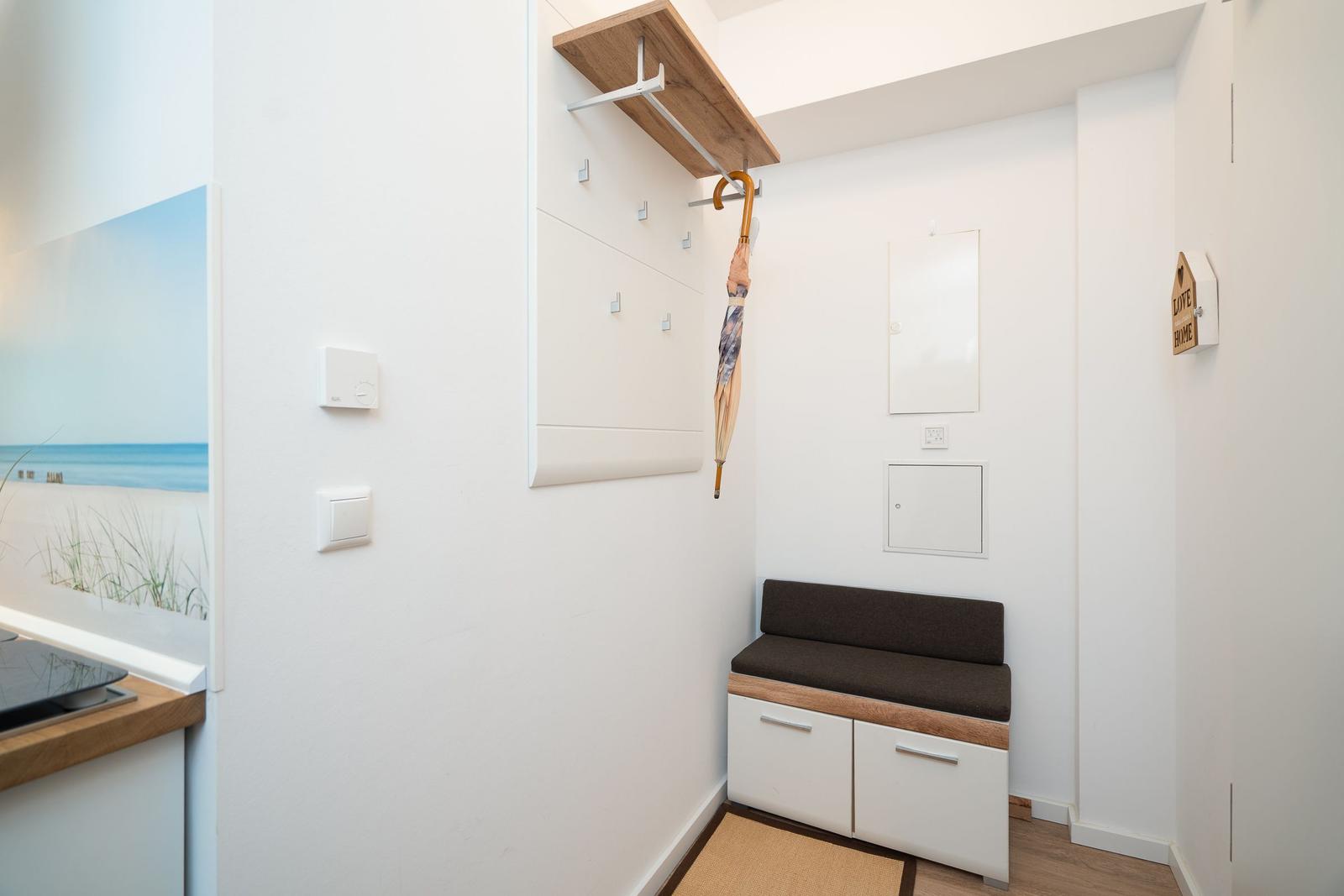 Entrance with bench, shelf, and wall cabinet. Wall art shows beach.