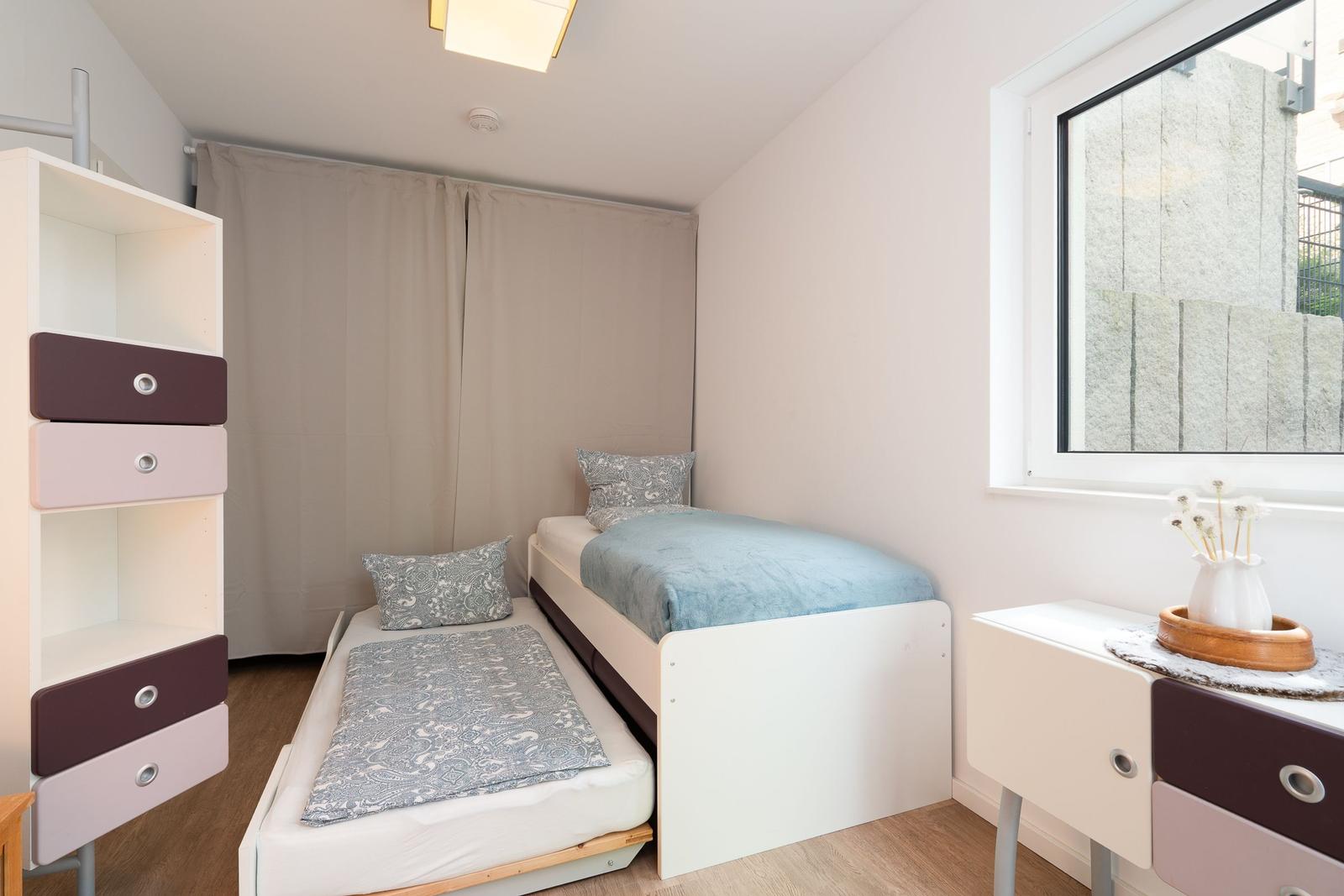 A bedroom with a bed and a sleeping space. There is a window and a wardrobe.