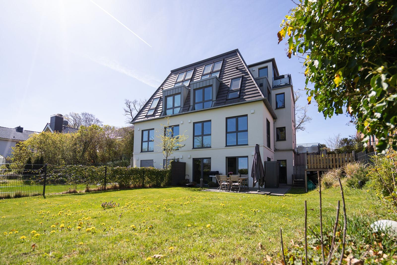 Modern villa with large garden and terrace. Multiple windows and skylights visible.